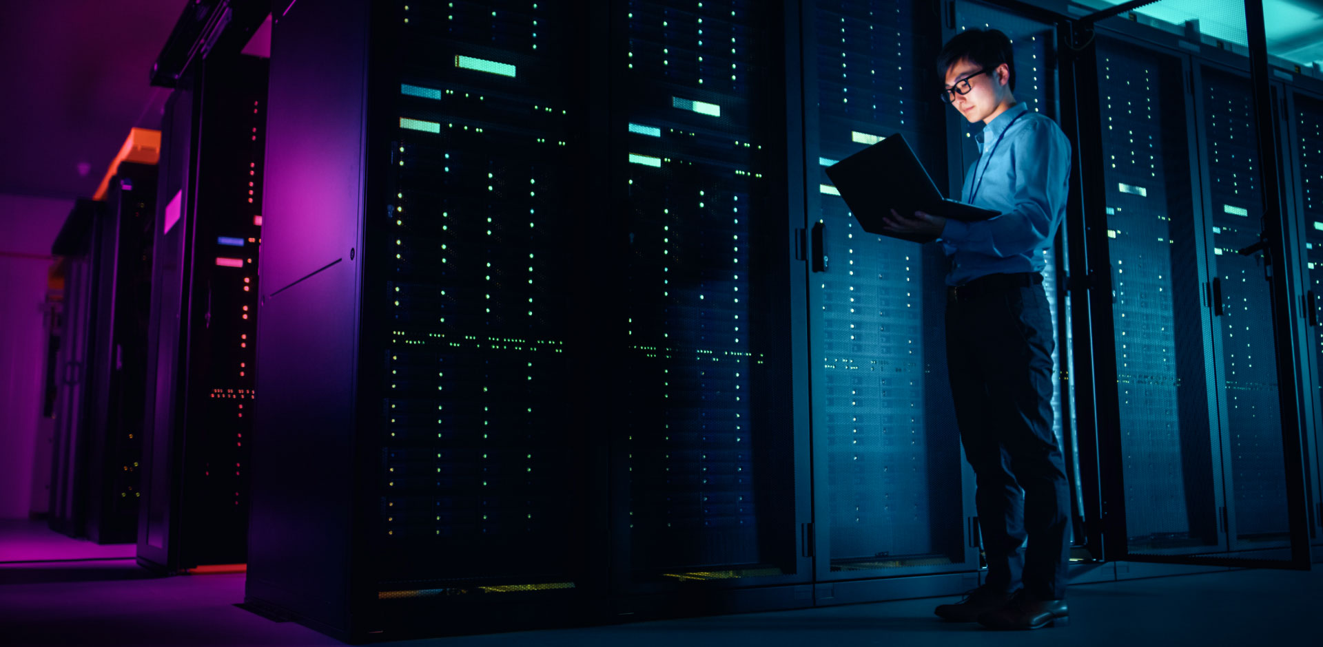 IT specialist using a laptop inside the server room